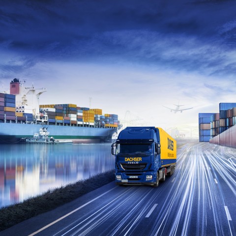 Camion DACHSER sur une route au crépuscule, avec un port et des navires en arrière-plan